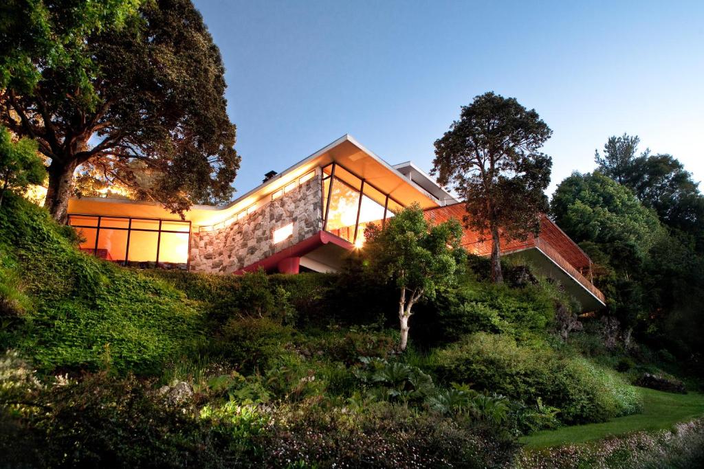 Low modern building of stone and glass set into a wooded slope above water