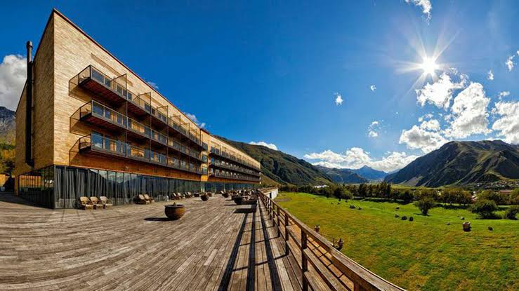 Long horizontal building with rows of windows facing a mountain valley