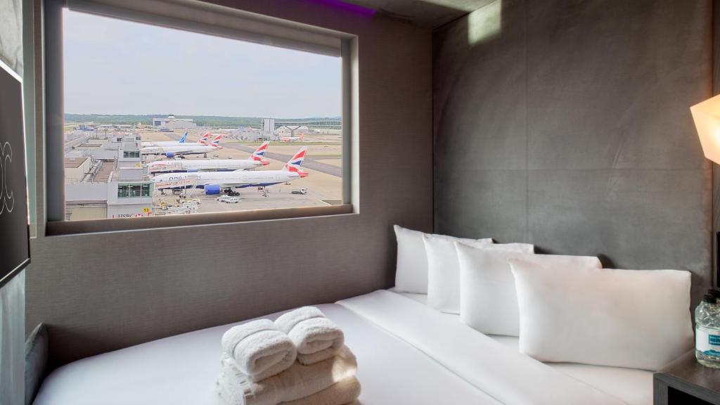 Compact hotel room with a bed against the wall and a broad glazed panel
