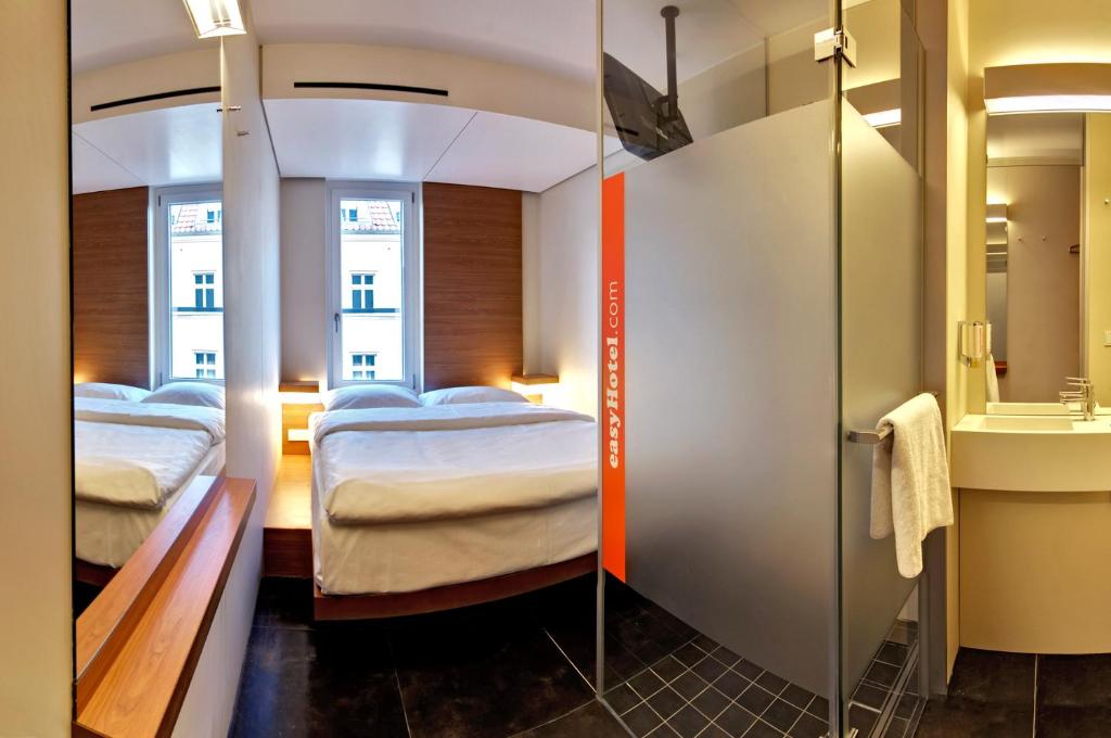 Small hotel room holding a bed, a narrow shelf and a window
